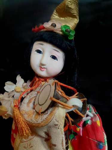 Muñeca japonesa tradicional con tambor tsuzumi y kimono rojo