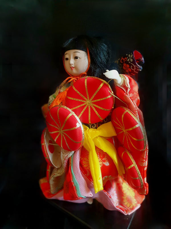 Muñeca japonesa antigua con sombreros tradicionales apilados, vista frontal