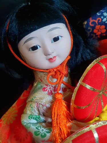 Muñeca japonesa antigua con sombreros y kimono rojo