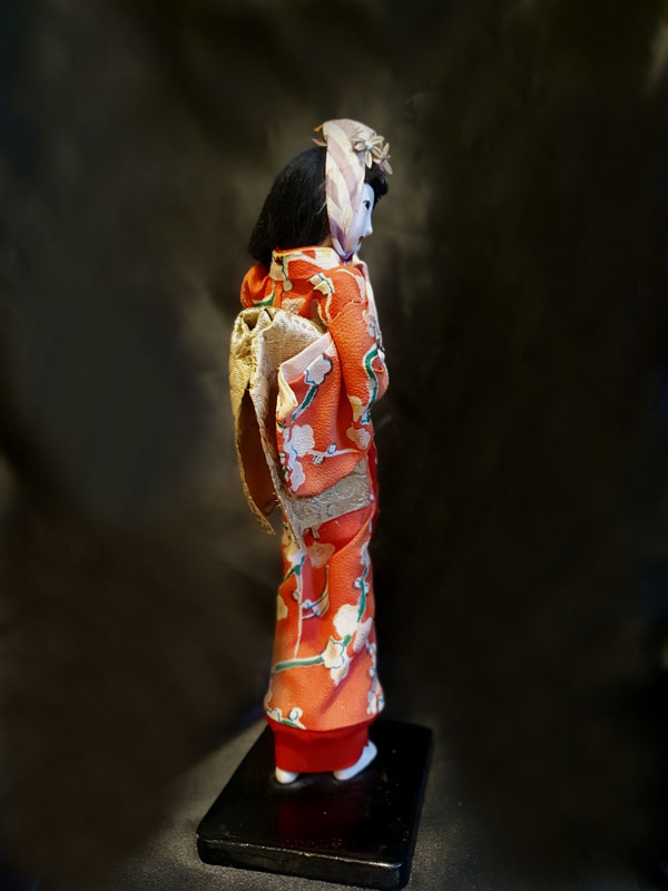 muñeca japonesa sobre mase de madera antiua con kimono rojo